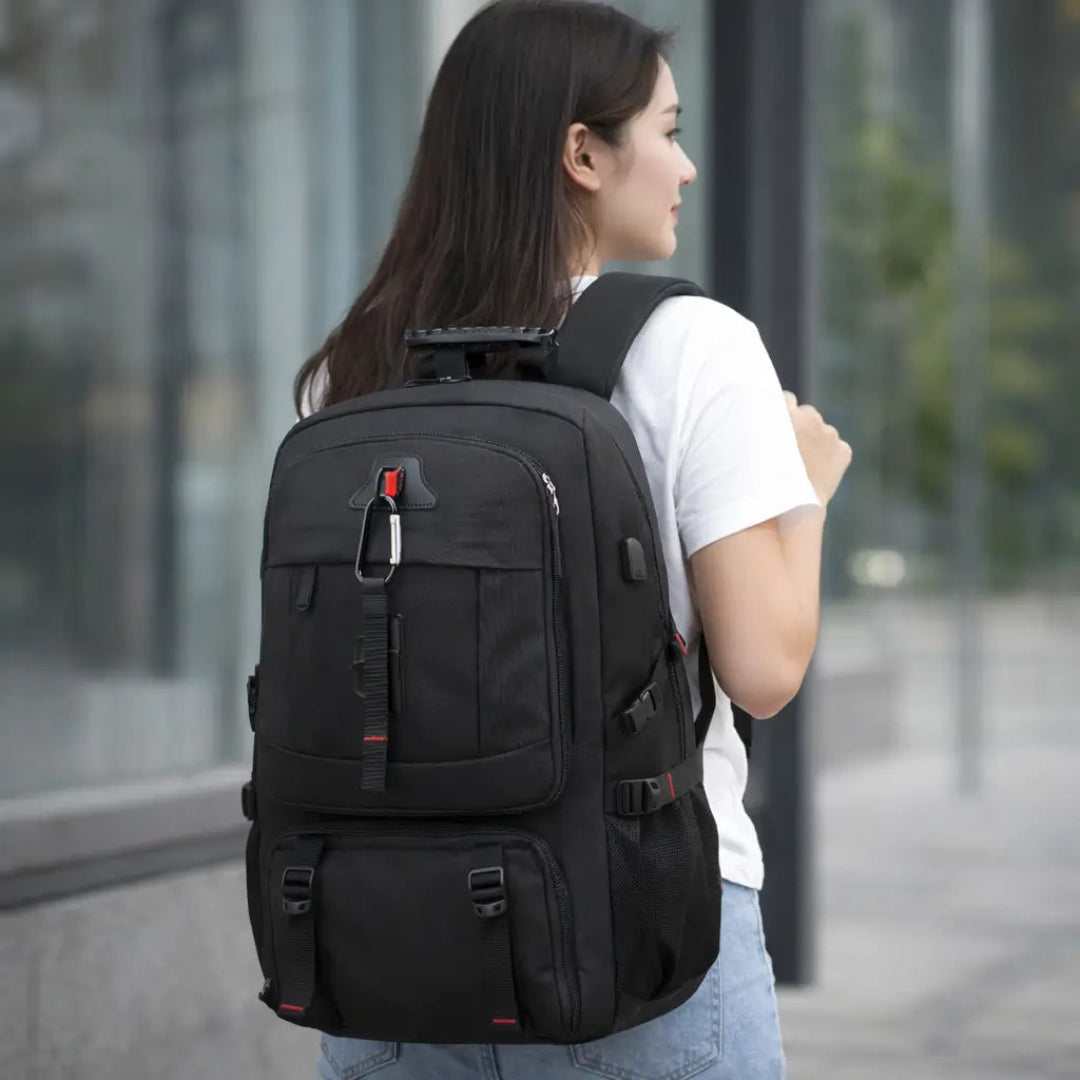 Mulher usando mochila de viagem preta grande com vários compartimentos em ambiente urbano